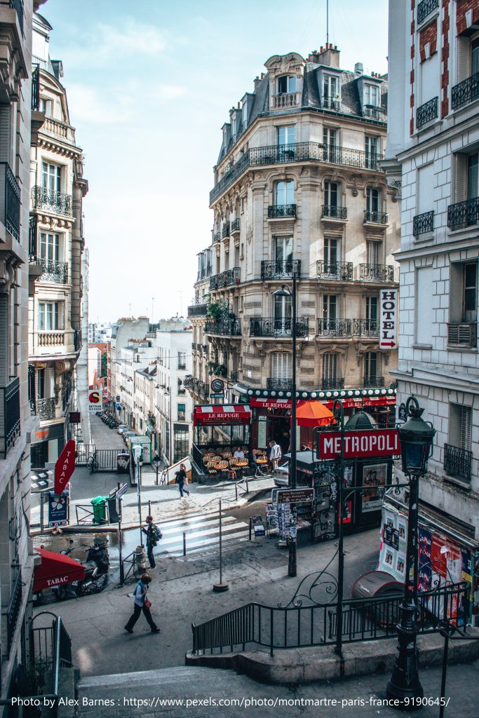 Promotional image showing a Parisian picture. Photo of Paris street with local shops and locals walking about.